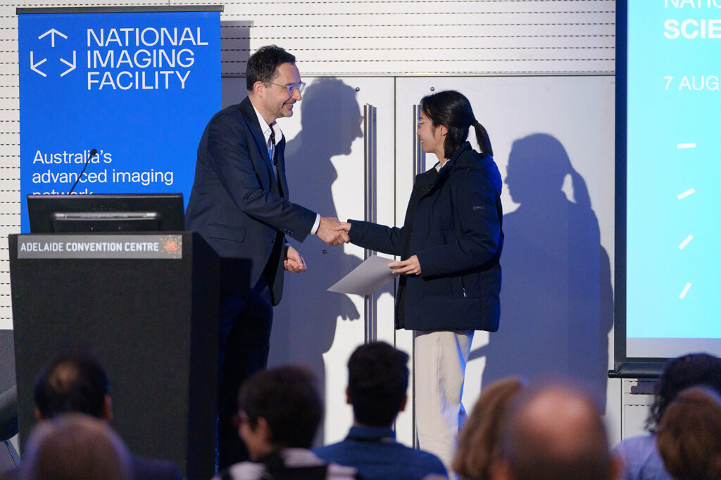 woman receiving award shaking hands with man up on stage