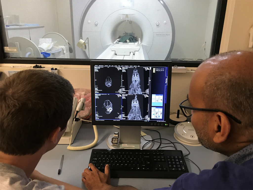 Two men looking at a screen in front of an MRI